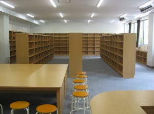 3階建ての仮設校舎の内観2。タイルカーペット地の部屋に棚が並べられている。