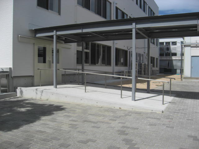 3階建ての仮設校舎の外観2。渡り廊下。校舎の出入口から緩やかなスロープが渡り廊下に続いている様子。