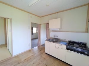 応急仮設住宅の内観1。流し台、コンロ、収納を備えた明るいキッチン。