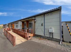 応急仮設住宅の外観3。右斜めから。緩やかなスロープが玄関に繋がっている。