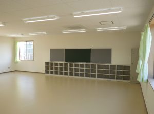 児童クラブの内観2。右斜めから。窓には黄緑色のカーテンがかかっている。