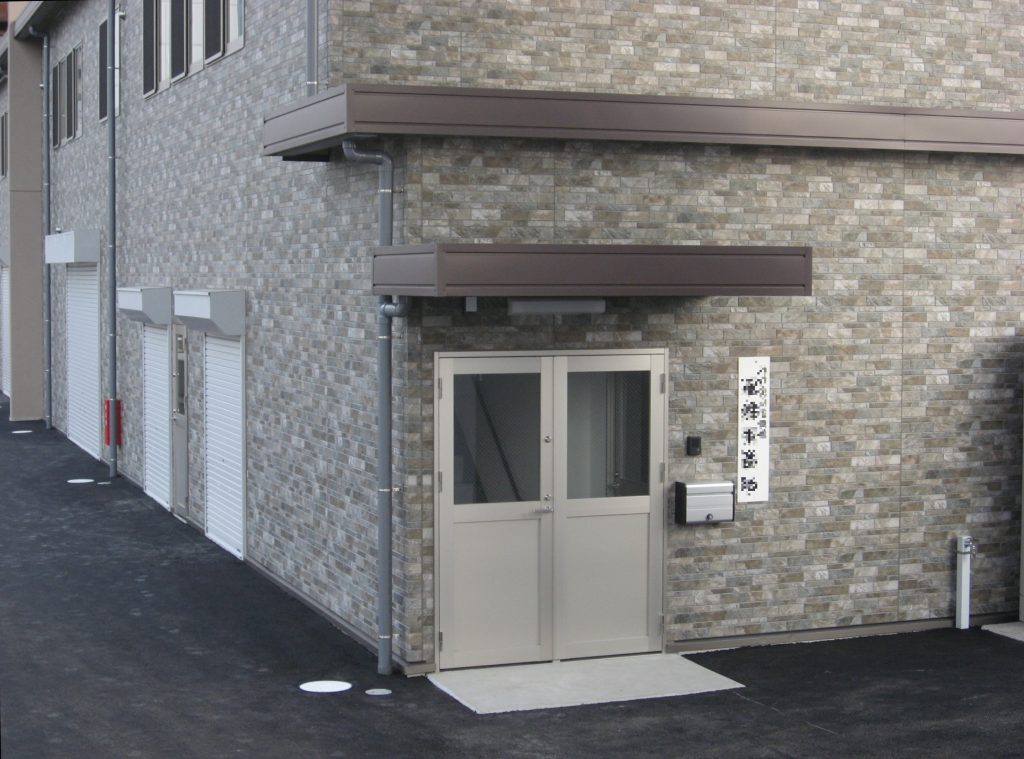 2階建て事務所の外観3。建物裏側、屋根と庇を備えた事務所出入口。