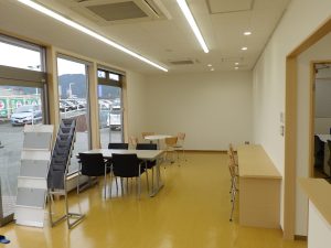 カーディーラー店舗の内観1。商談用のスペースに、机と椅子が3セット置かれている。