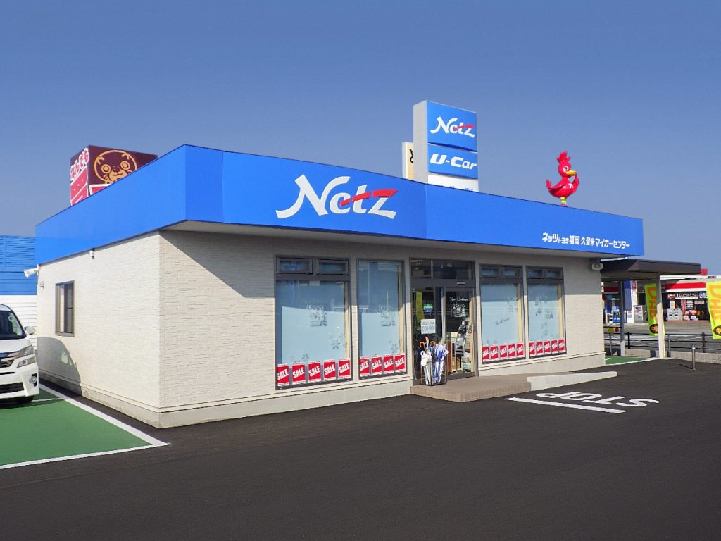 カーディーラー店舗の外観1。左斜めからの全景で、玄関部分を挟んで大きなFIX窓が4枚はめ込まれている。