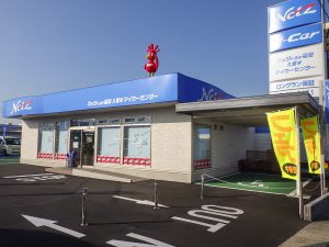 カーディーラー店舗の外観2。右斜めから。駐車場の優先スペースから店舗の玄関までが軒下で繋がっている様子。