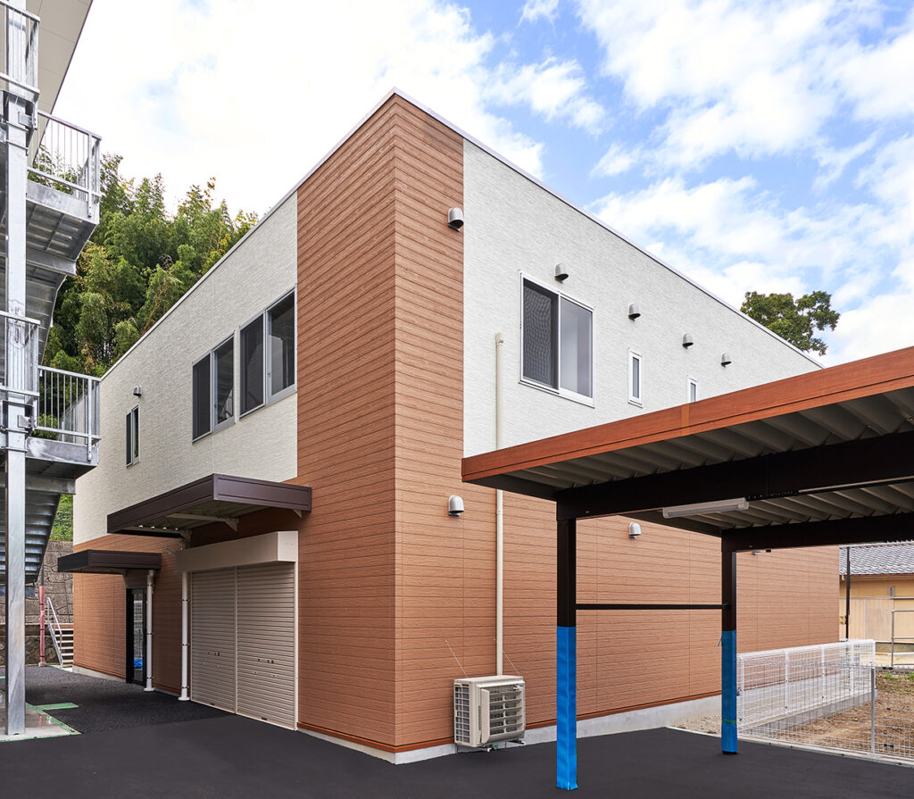 2階建て倉庫兼事務所の外観。右斜めからの全景。軽量手動シャッターと出入口が写っている。