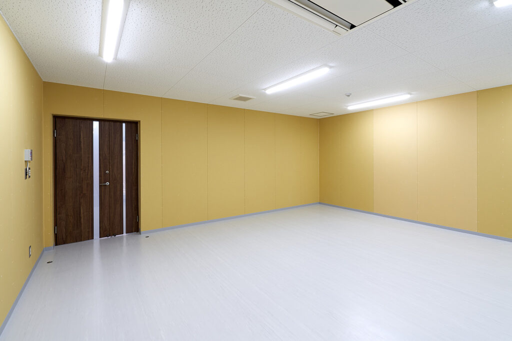 2階建て倉庫兼事務所の防災倉庫内観。室内から写した部屋の出入り口。壁は明るい黄系カラー。