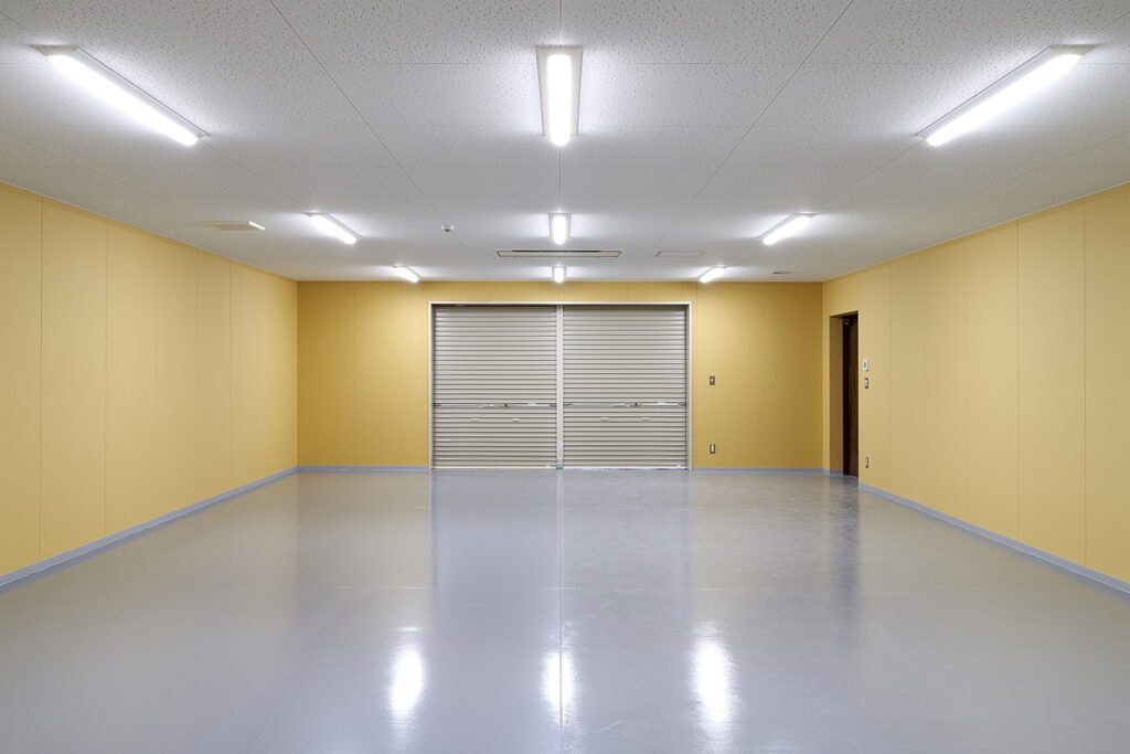 防災倉庫の室内から写した軽量手動シャッターとドア。