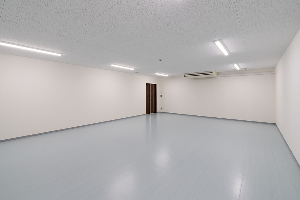 2階建て倉庫兼事務所の倉庫内観。奥側から写した入口ドアとエアコン。