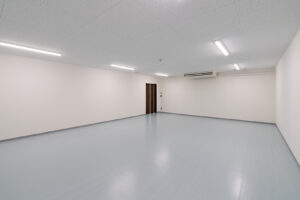 2階建て倉庫兼事務所の倉庫内観。奥側から写した入口ドアとエアコン。