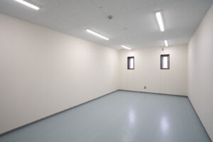 2階建て倉庫兼事務所の男子更衣室内観。入口から写した2枚の縦滑り出し窓。